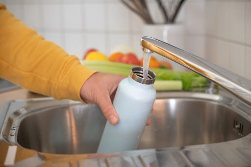 someone filling up their metal water bottle