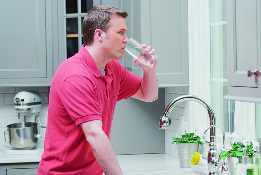 Man Drinking Glass of Water in Kitchen